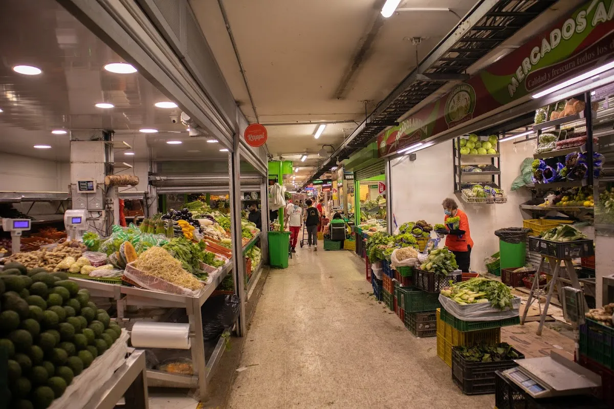 Vibrant vegetable and fruit stalls with vendors inside Paloquemao Market in Bogotá
